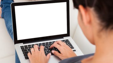 sylwetka kobiety siedzącej tyłem. Przed nią znajduje się otwarty laptop, na którym kobieta pisze.